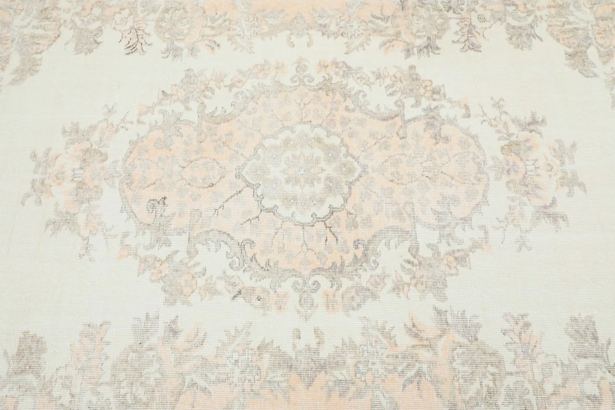 Detailed view of the central medallion and surrounding floral motifs in cream, orange, and gray.