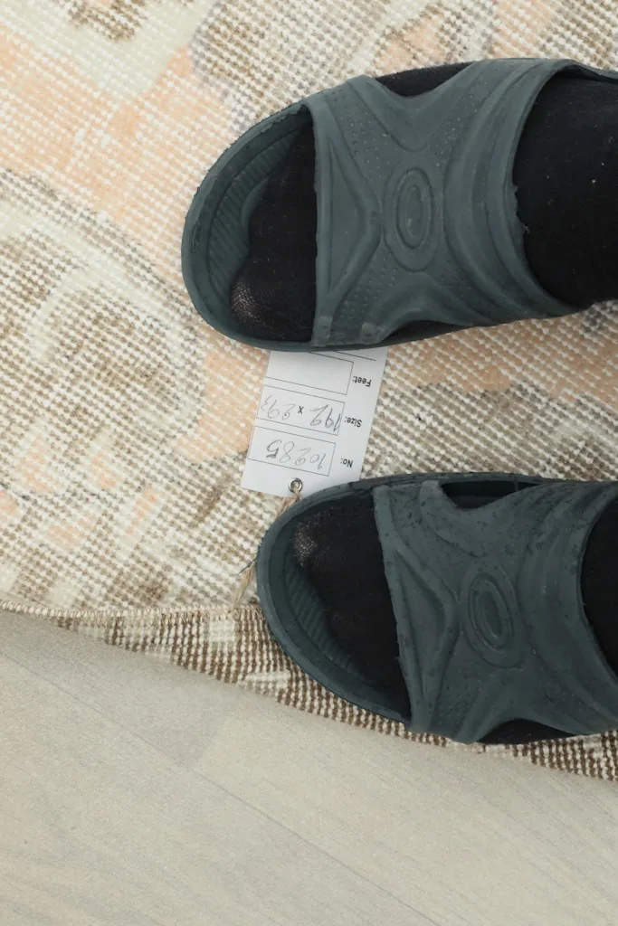 Feet on the rug next to a tag displaying the dimensions 6'4" x 9'7" and other rug details.