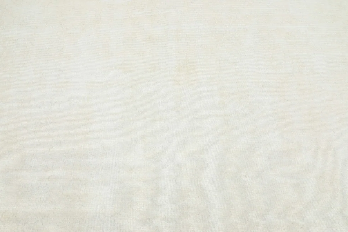 Close-up detail of the ivory wool pile, revealing the distressed finish and very faint underlying patterns.