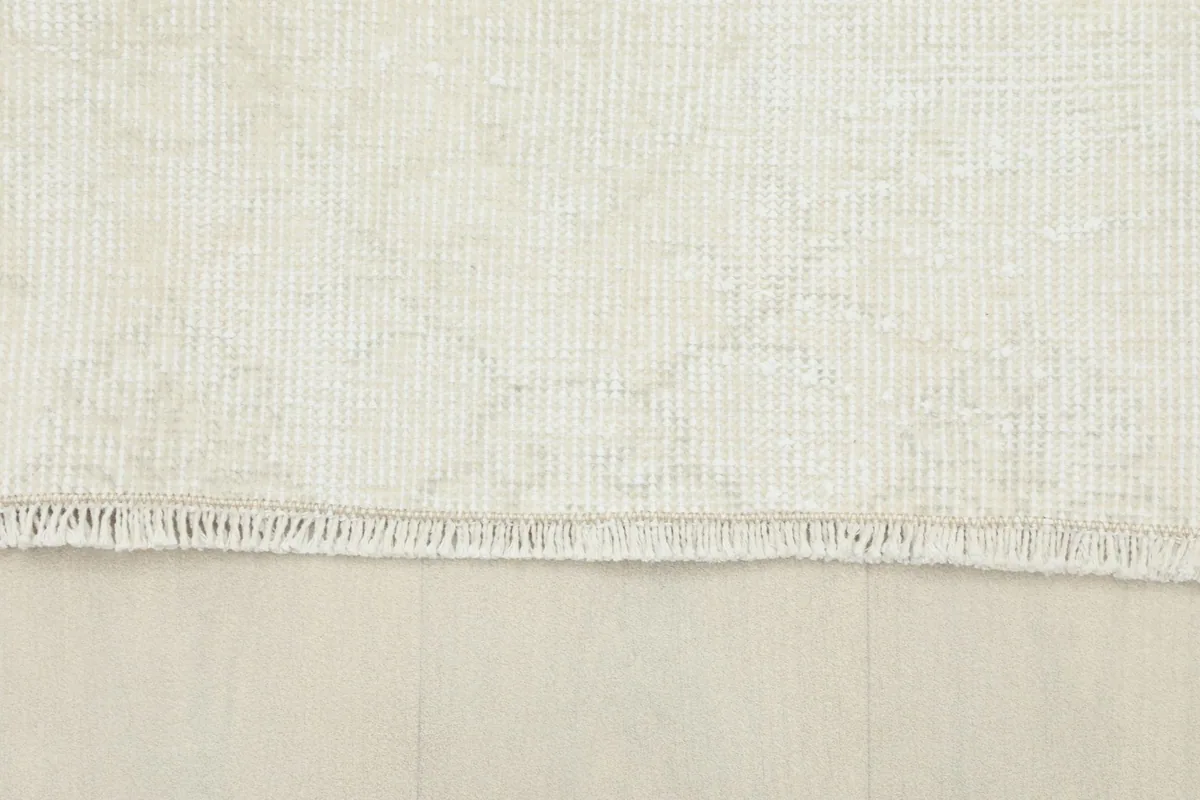 Detail of the short, natural fringe at the end of the ivory vintage area rug.