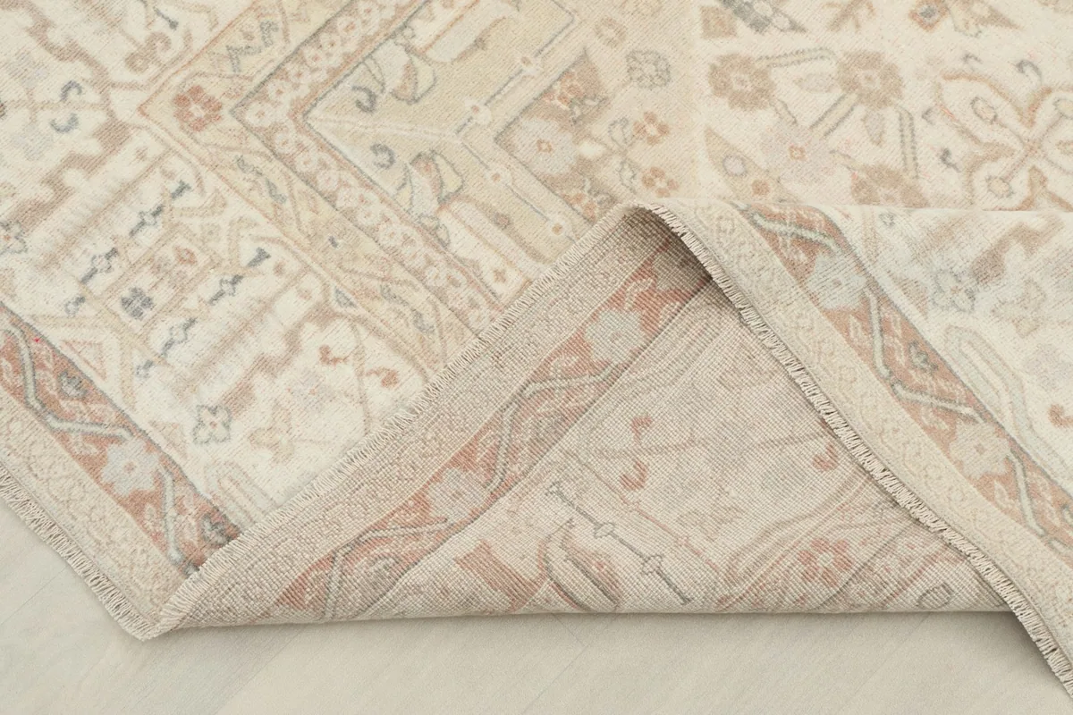 Corner of the rug folded back, revealing the reverse side and hand-knotted construction.