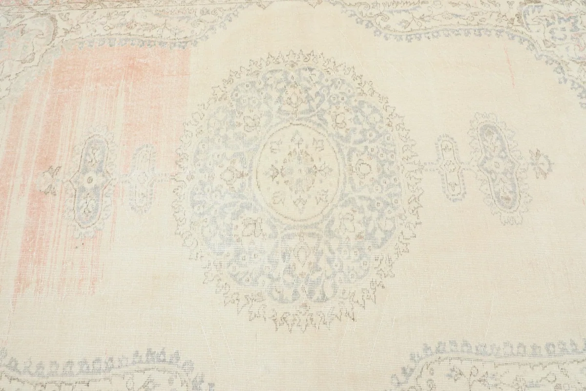 Close-up of the central gray medallion motif against the faded cream field of the vintage rug