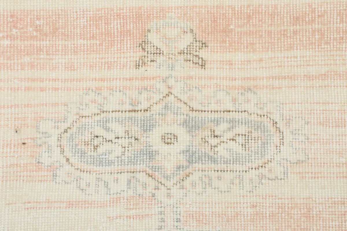 Detailed view of the distressed rose section and a smaller gray motif in the rug's upper portion