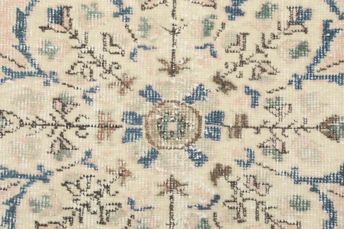 Macro view of the wool pile, showing the individual knots and the soft, worn texture of the vintage rug.