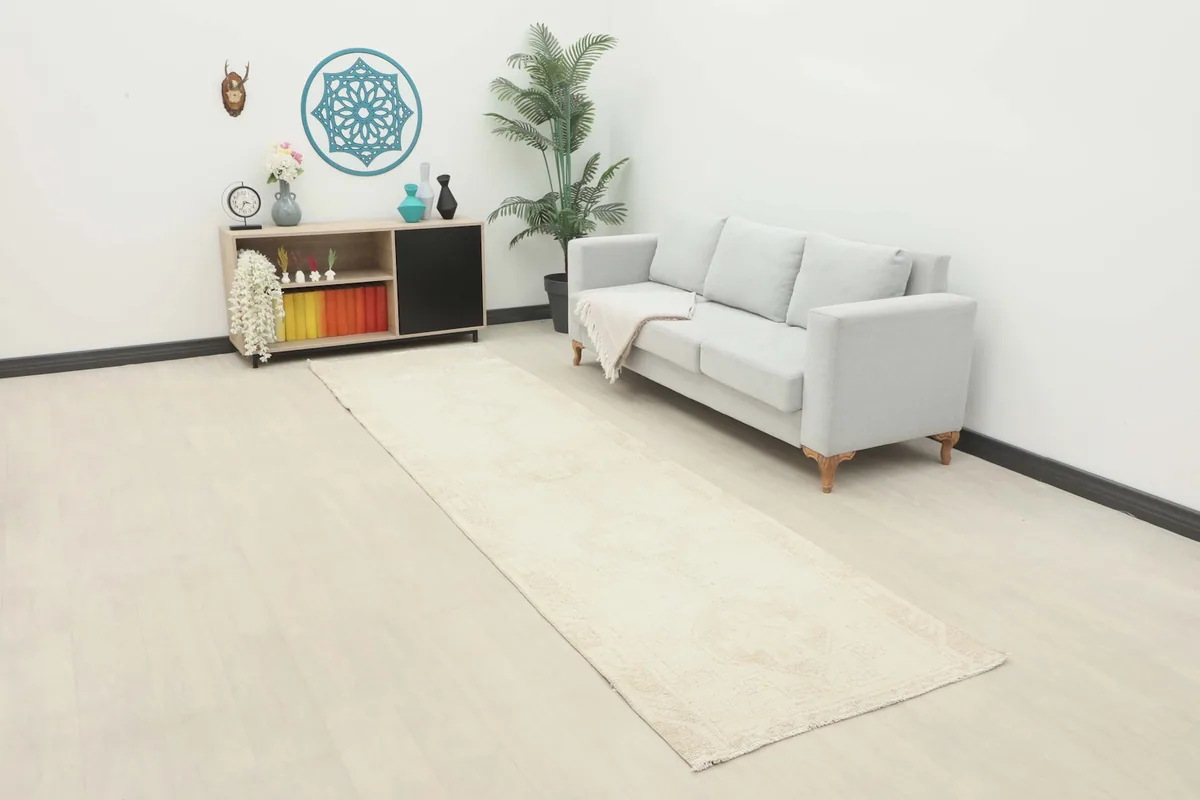 Runner rug placed in a modern room setting, extending from a cabinet towards a light gray sofa, showing its full length.