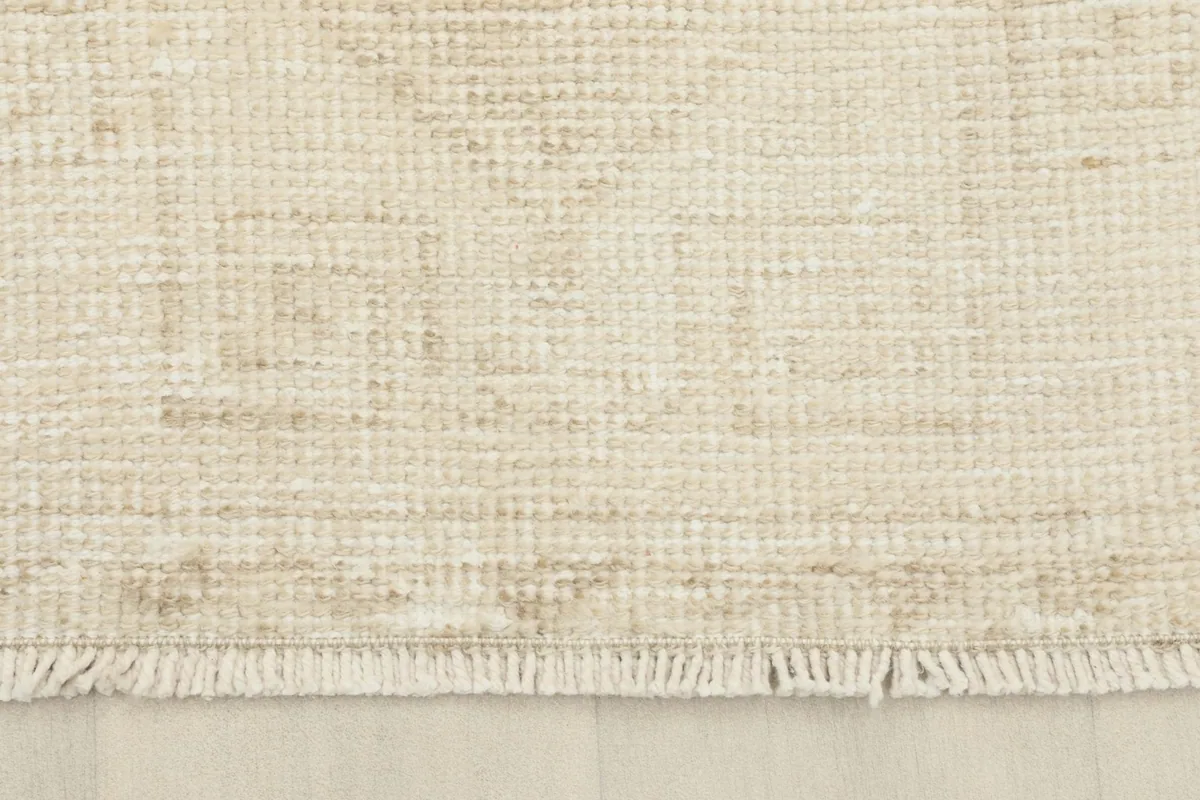 Close-up of the rug's fringe and the tightly woven edge, revealing the wool pile and cotton foundation.