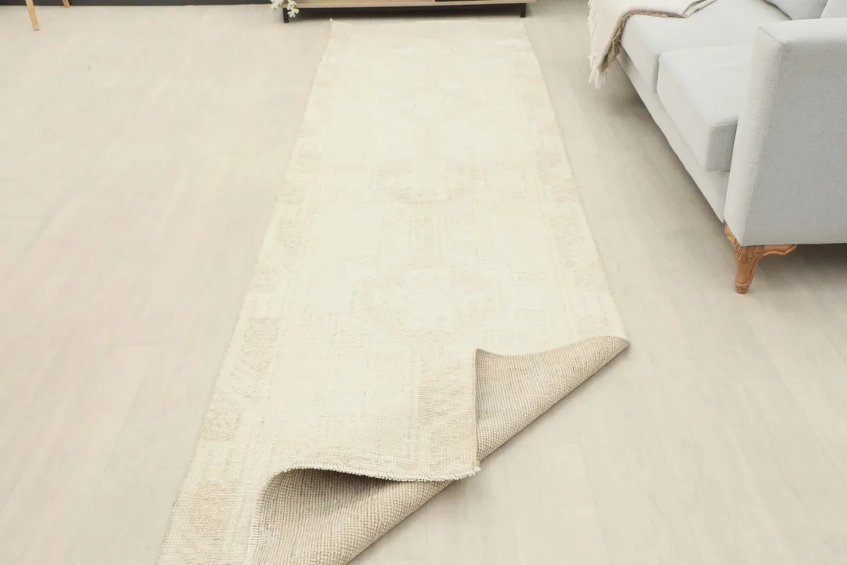 The runner rug in a room setting, with one end folded back to show the reverse side and thickness.