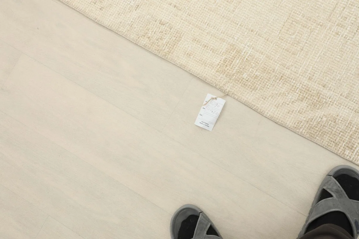 Overhead view showing the rug's scale next to a pair of feet, providing a sense of its length in a room.