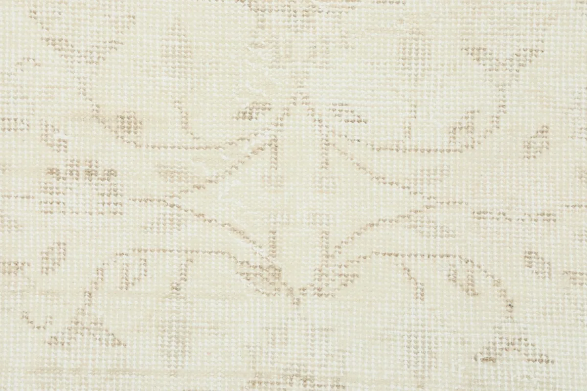 Detailed close-up of the hand-knotted wool pile and a specific floral motif in beige.