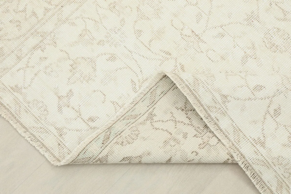 Corner of the rug folded back to show the cotton foundation and the reverse side of the knotting.