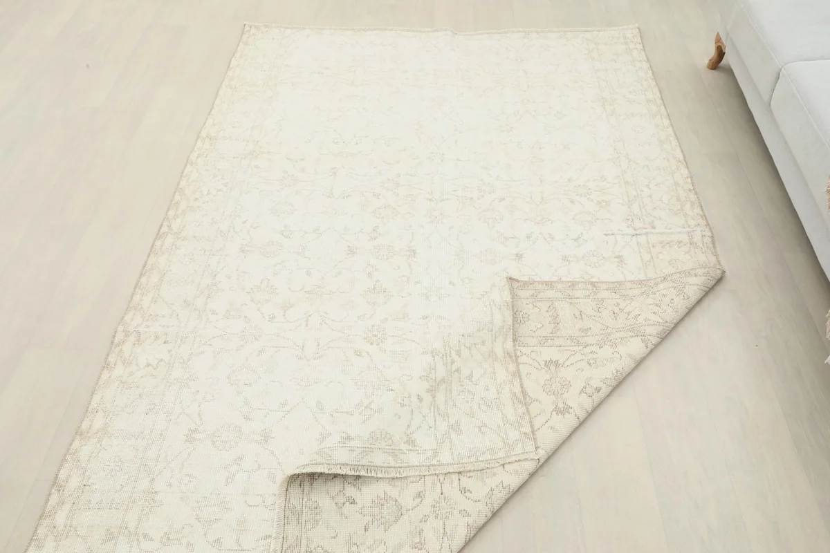 Rug with a corner folded over, illustrating its flexibility and the vintage appearance of the back.