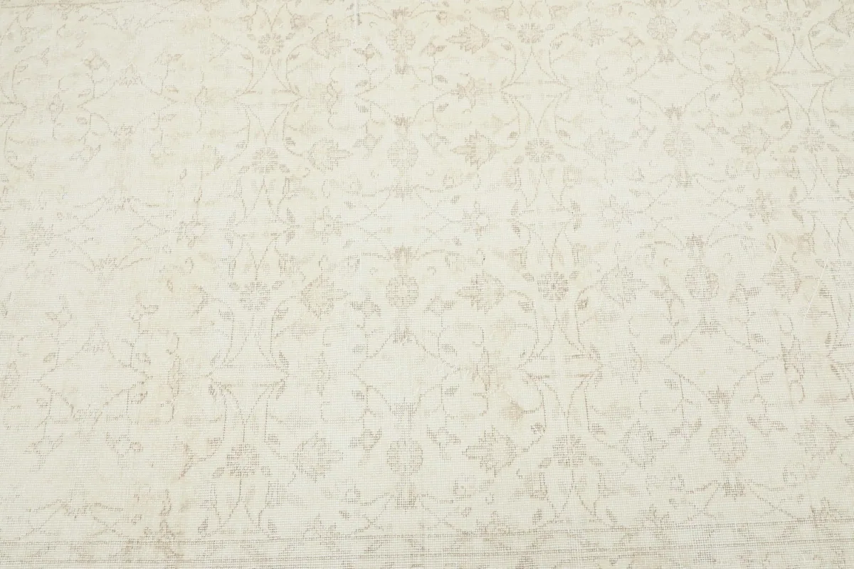Close-up overhead view of the ivory rug's field, revealing the delicate beige floral design.
