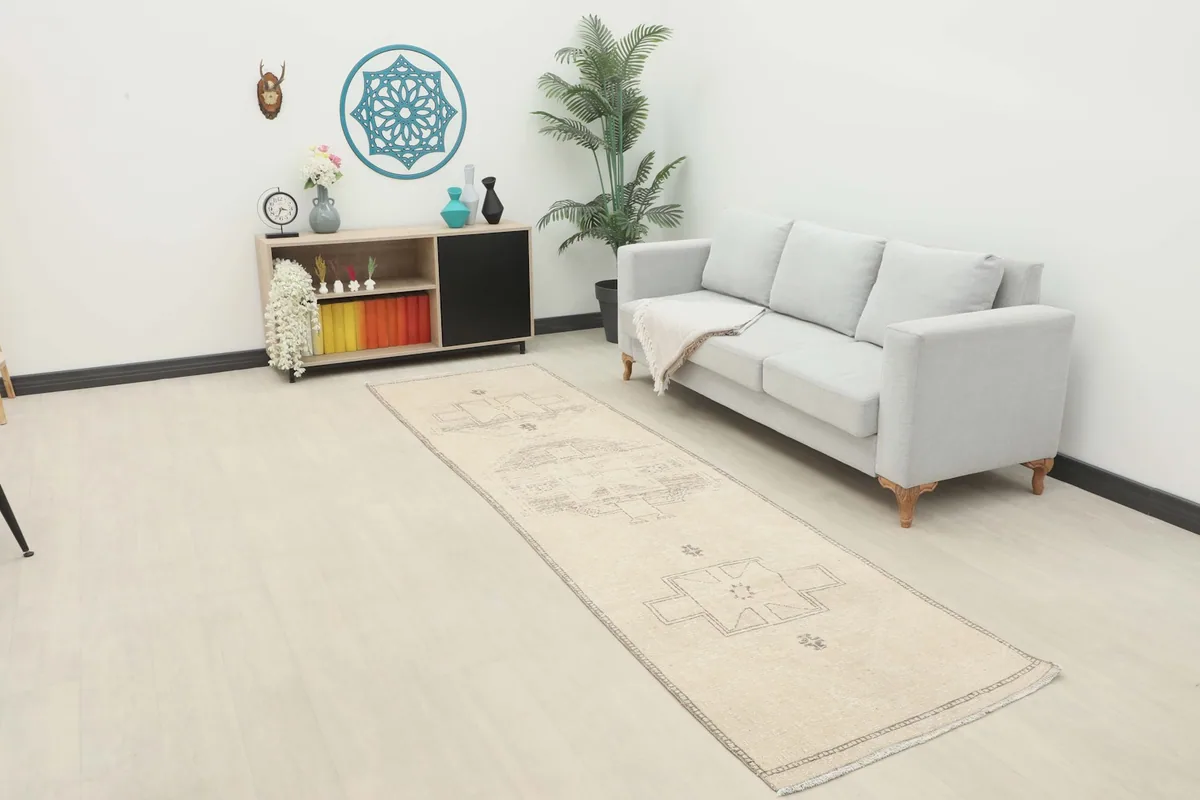 Long view of the ivory and charcoal runner rug placed in a modern living space with a light sofa.