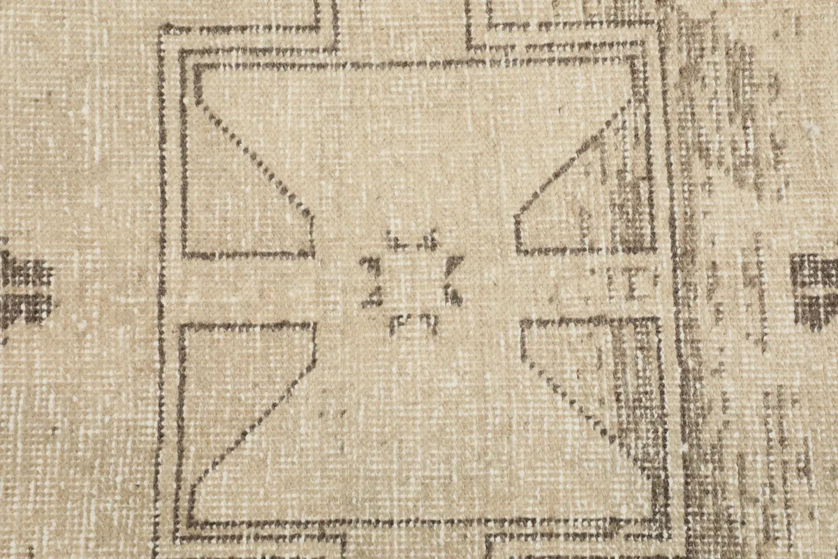 Close-up of a distinct charcoal geometric motif within the ivory field, showing knot detail.