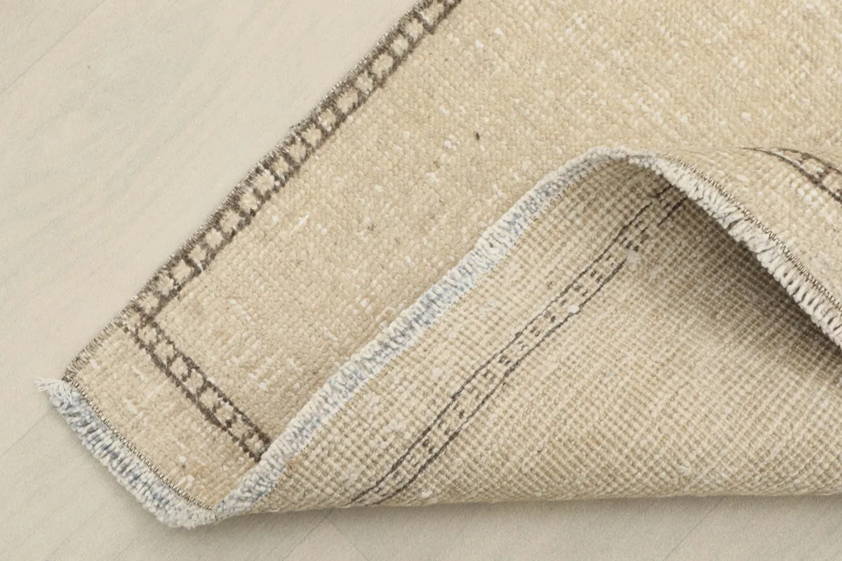 View showing the folded corner of the rug, revealing its cotton foundation and hand-knotted construction.