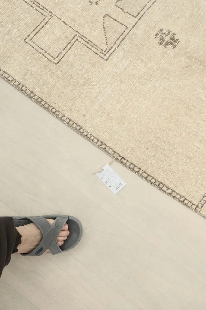 Top-down view of the rug next to a foot, providing scale and showing the texture of the low pile.