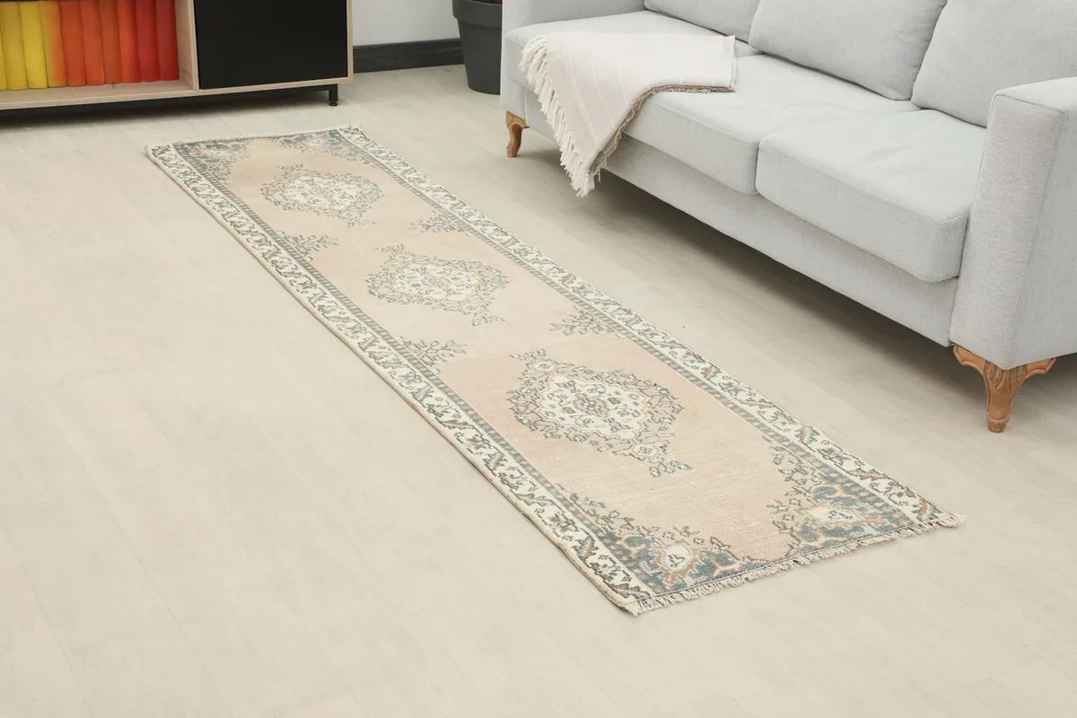 Angled view of the runner rug placed in a room next to a light gray sofa.