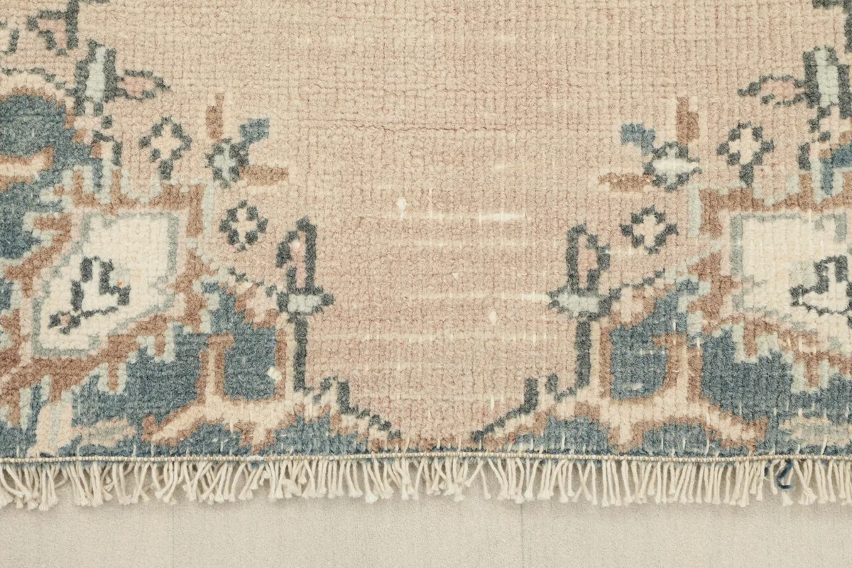 Close-up of the rug's fringe and the border design at one end.
