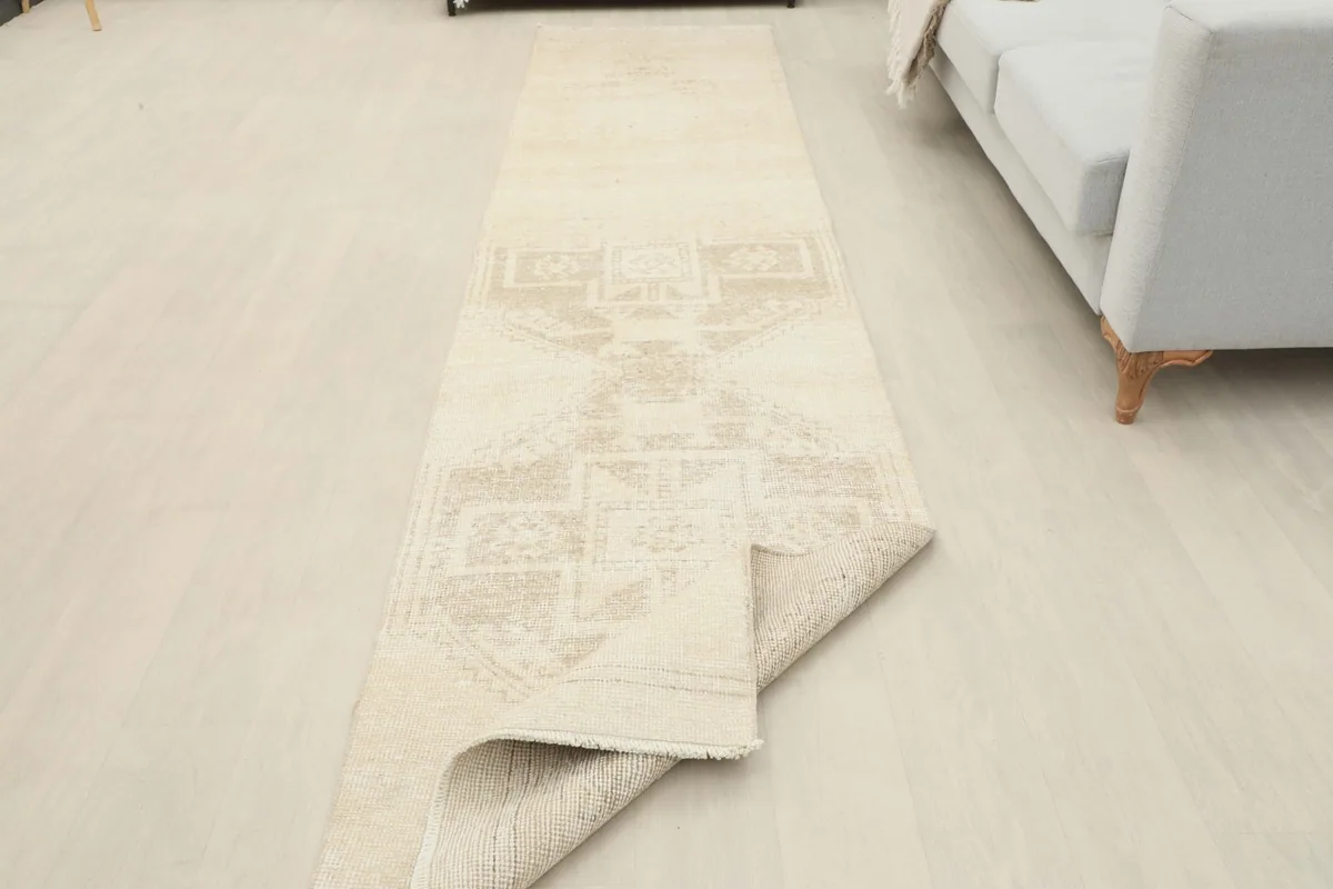 Full length view of the runner rug in a room, with one end slightly folded to show its flexibility and construction.