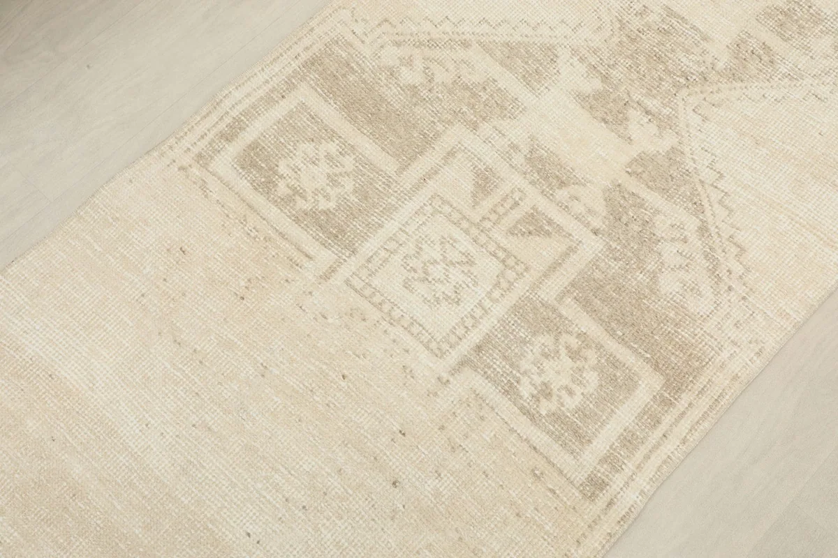Close-up of the geometric design elements and the distressed texture of the wool pile in the rug's central area.