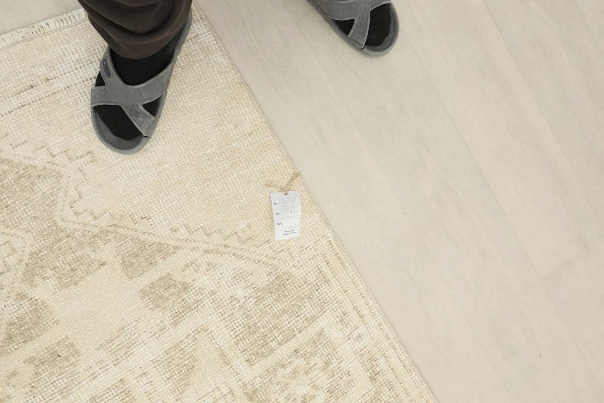 Overhead view showing a person's feet near the rug, emphasizing its scale and placement in a living space.