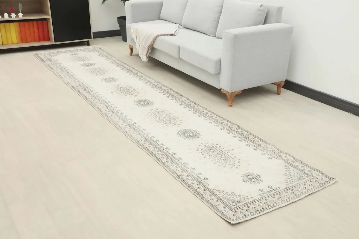 Angle view of the runner rug extending along a light-colored floor next to a sofa and cabinet.