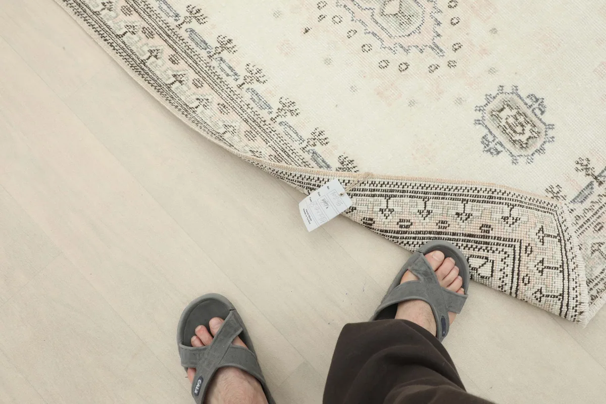 Close-up of the rug's pile and a foot for scale, illustrating the low pile height and soft texture.