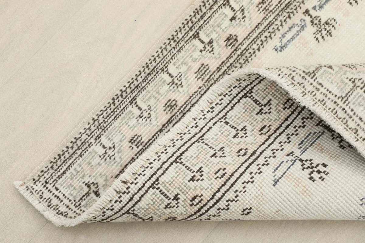 Corner of the runner folded back, showing the cotton foundation and the reverse side of the hand-knotted construction.