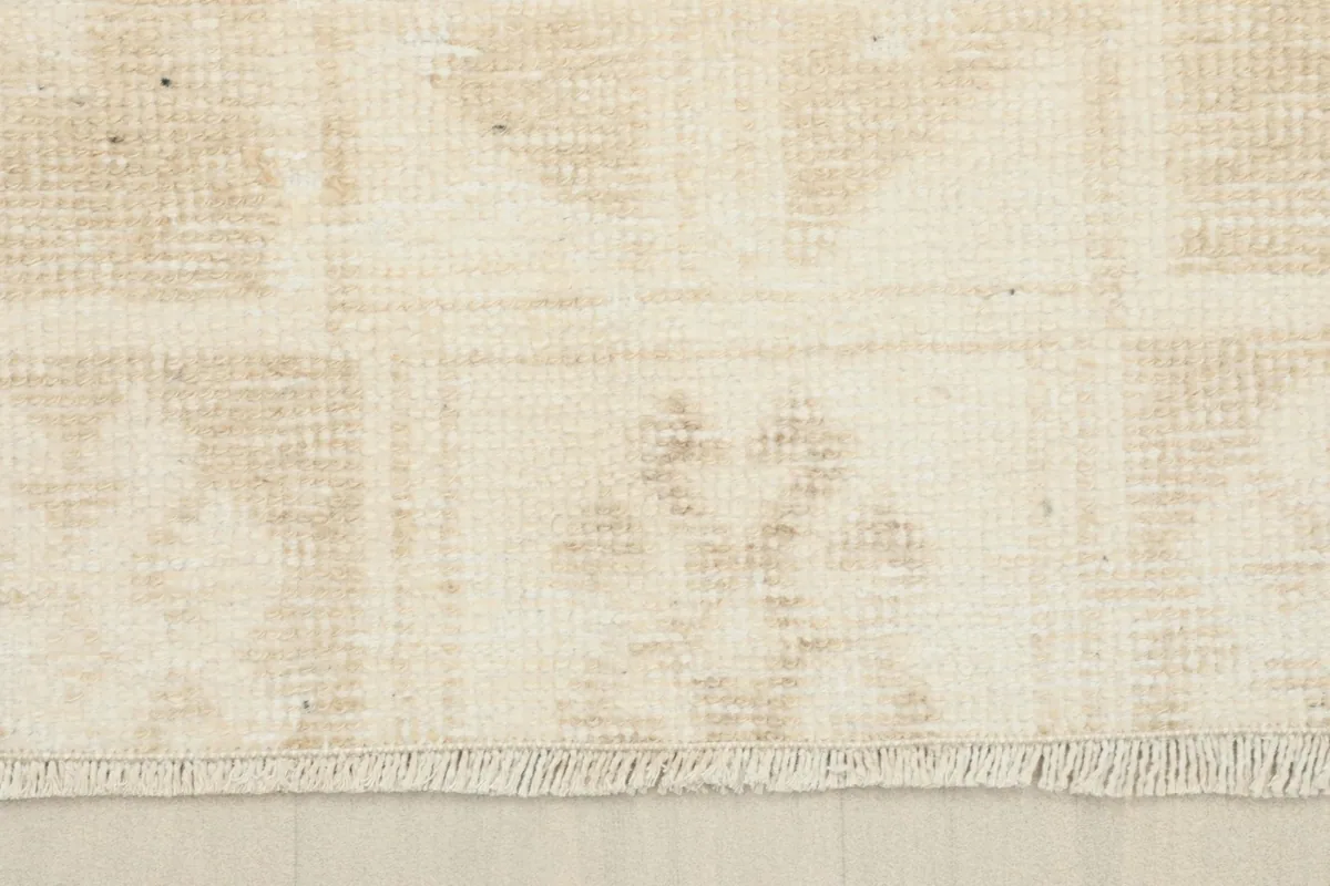 Detail of the short, subtle fringe at one end of the hand-knotted beige runner