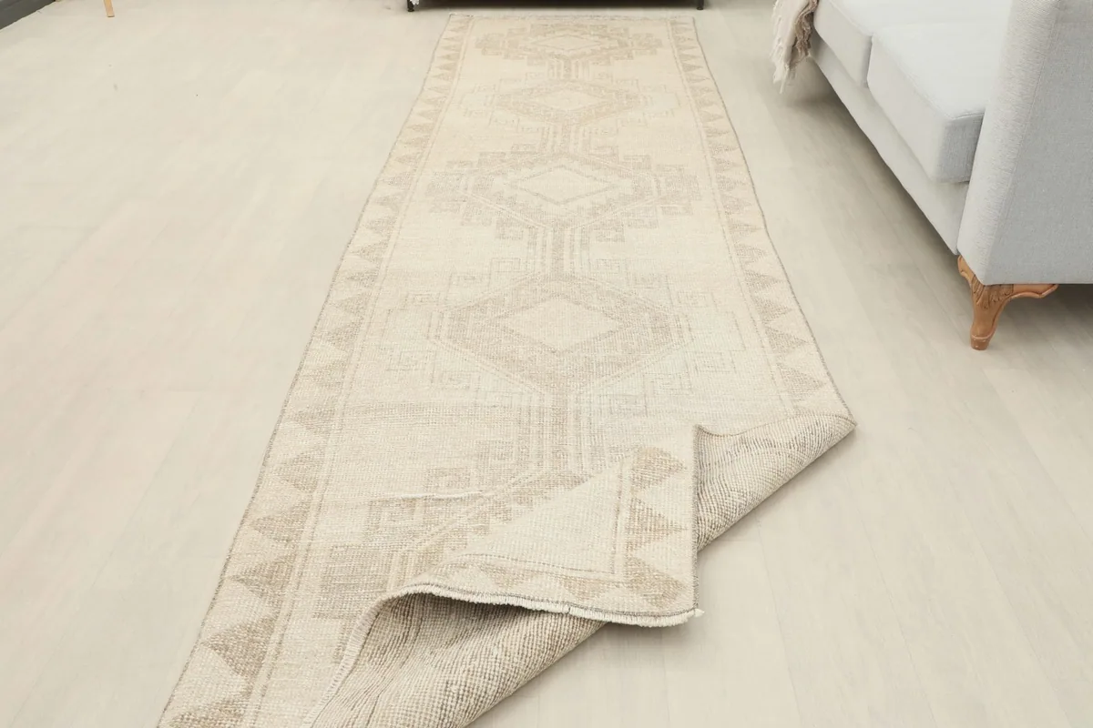 The runner rug partially unrolled in a room, highlighting its length and muted tones