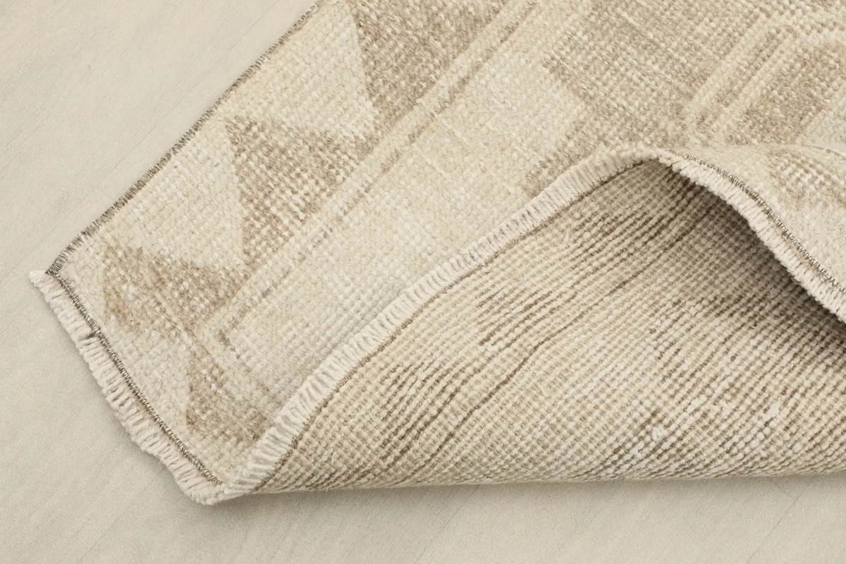 View of the rug folded to show the hand-knotted cotton foundation and pile thickness