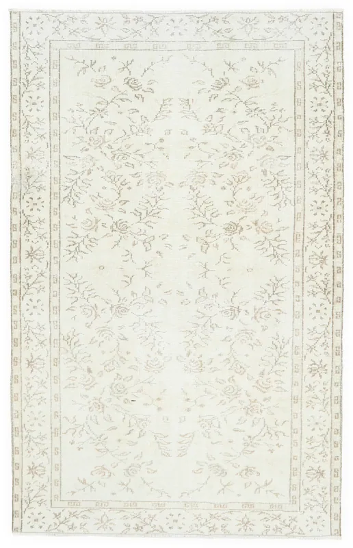 Full overhead view of the ivory and tan floral vintage Anatolian rug on a white background.