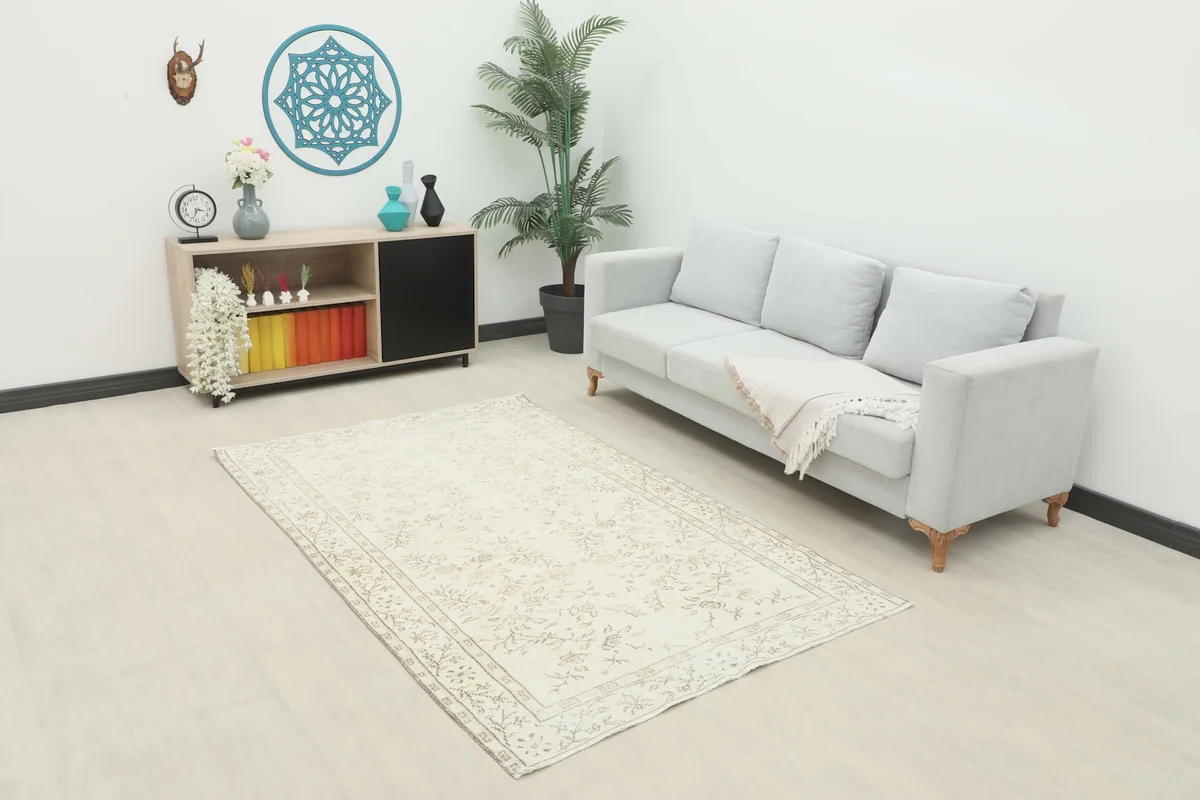 Ivory and tan rug in a living room setting with a light gray sofa and wooden console.