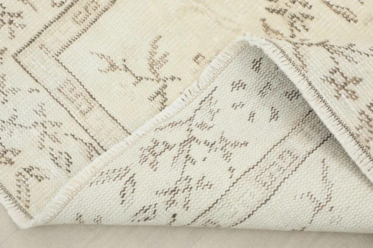 Folded corner of the rug revealing the cotton foundation and hand-knotted construction.
