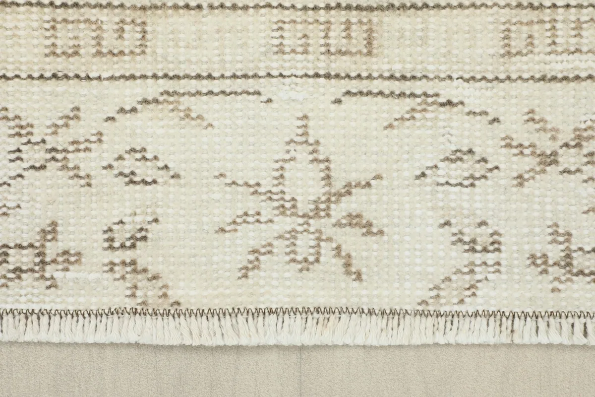 Close-up of the rug's fringe and a section of the tan border pattern.