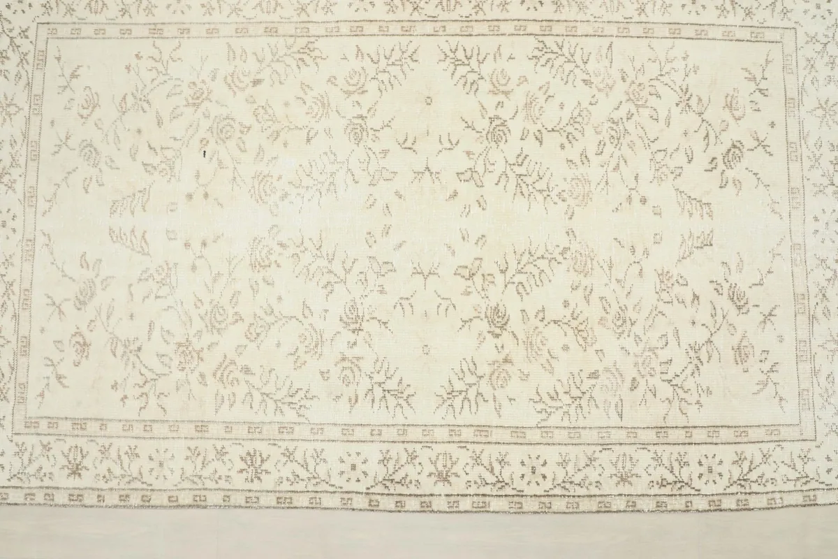 Overhead view of the rug, displaying the full ivory field and tan botanical pattern symmetry.