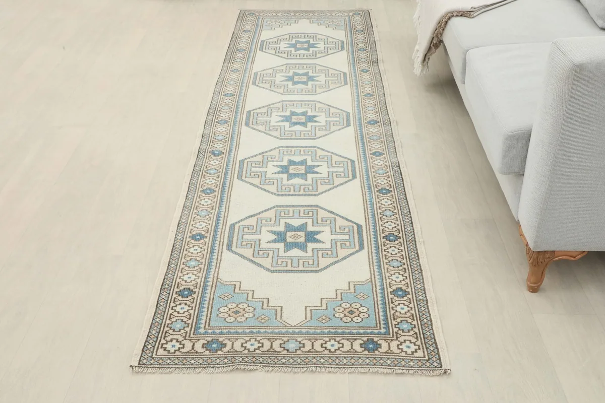 Full length view of the cream and blue runner rug in a bright room beside a sofa