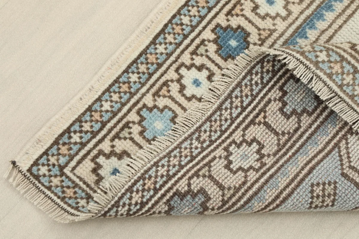 Corner of the rug folded back, showing the back of the hand-knotted construction