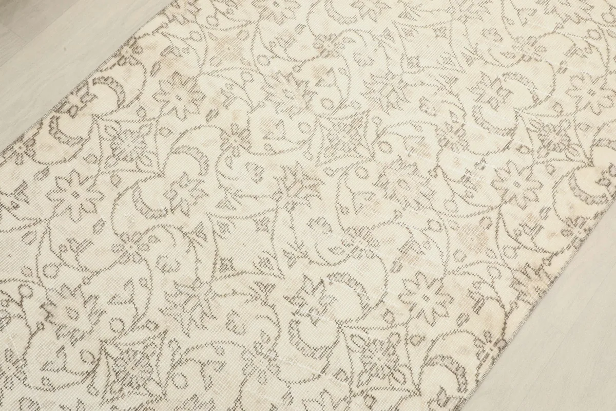 Angled close-up showing the intricate gray floral motifs on the beige field.