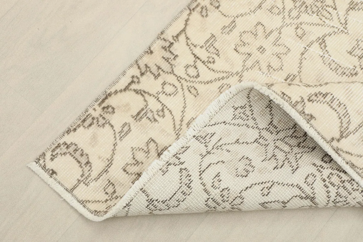 Corner of the rug folded back to show the cotton foundation and reverse side of the knots.