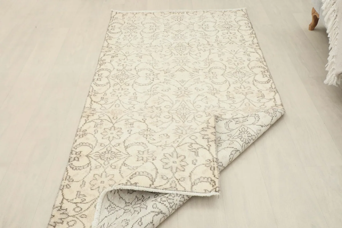 Rug partially folded, displaying both the front design and the clean cotton foundation.