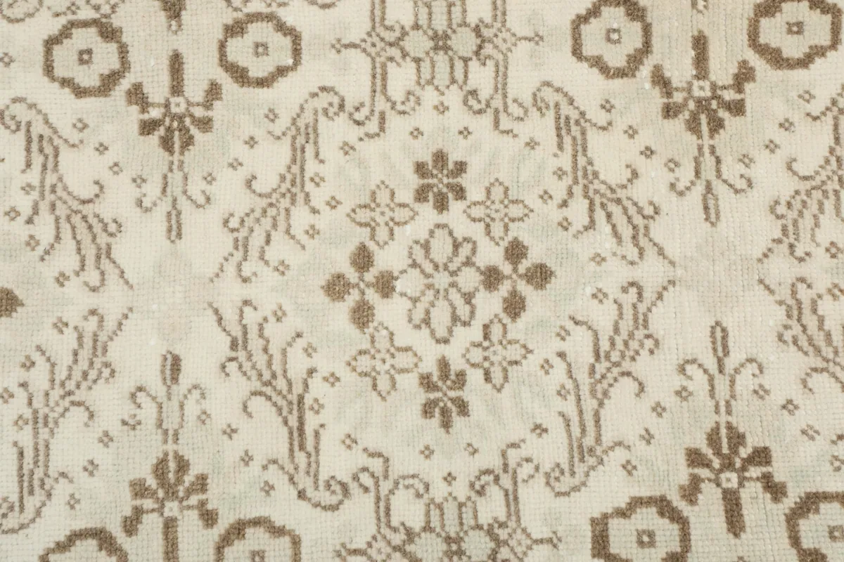 Detailed close-up of the rug's central floral and geometric patterns in ivory and tan.