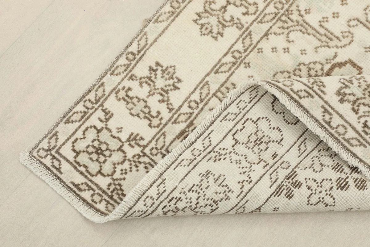 View of the rug's corner folded to show the hand-knotted cotton foundation and wool pile.