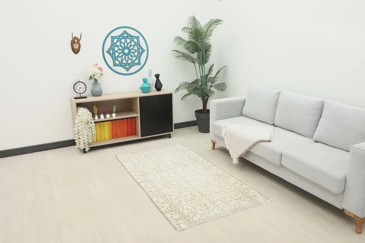 Ivory and tan floral rug placed in a modern living room setting with a light gray couch