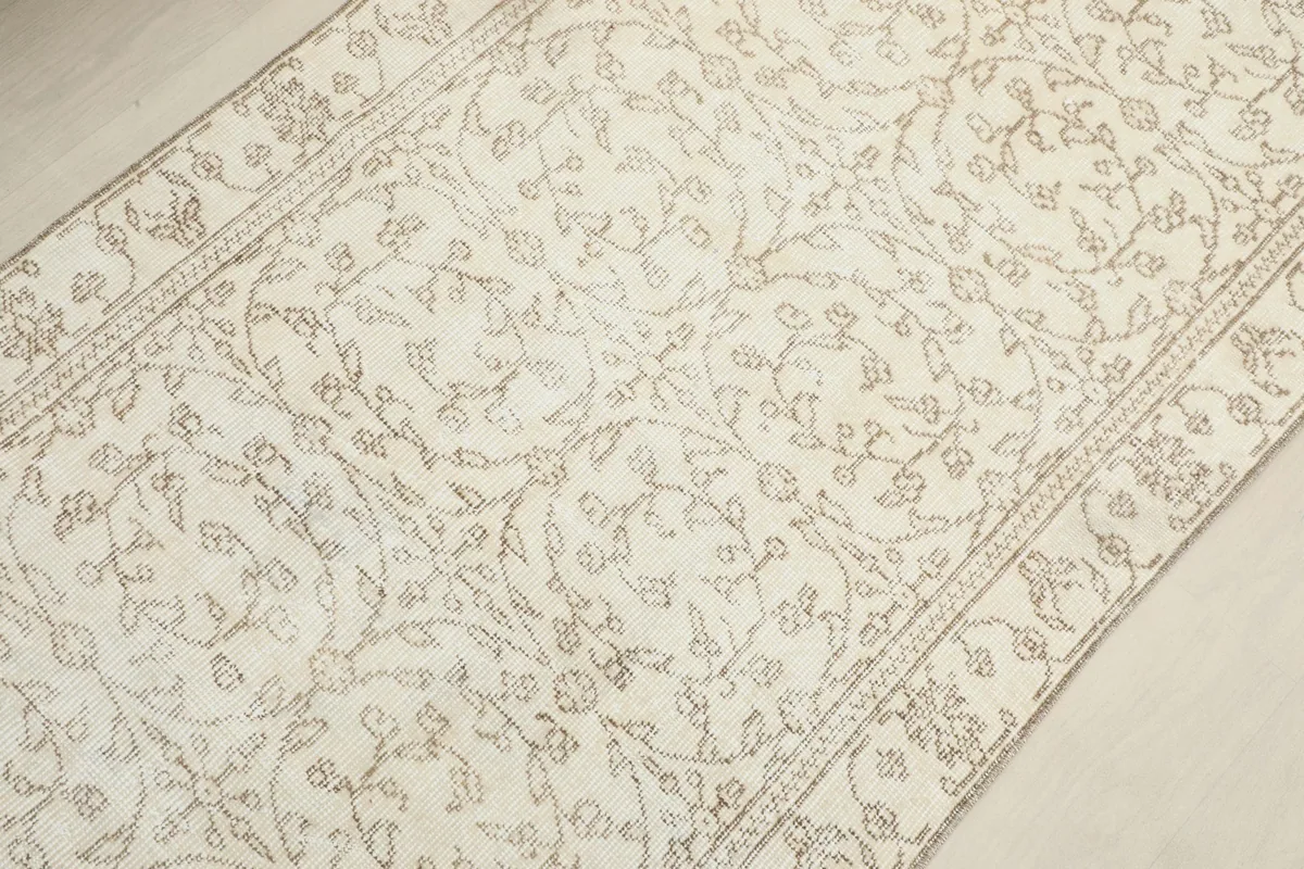 Detailed overhead shot of the rug's central floral design and lighter tan tones