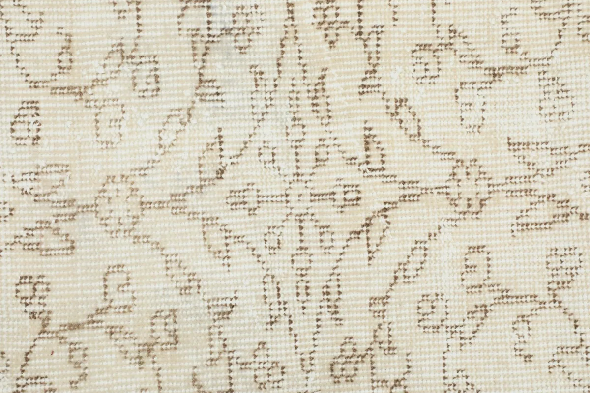 Close-up of the intricate hand-knotted floral and vine patterns on the rug's ivory background