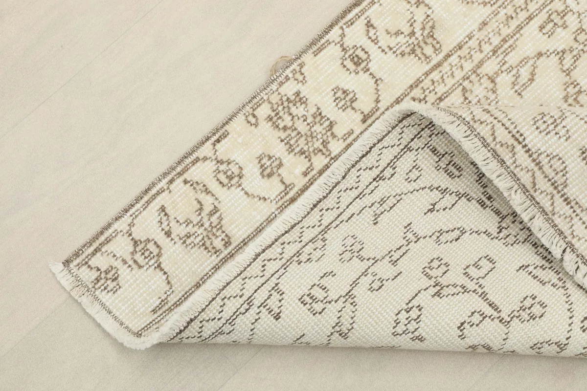 Corner of the rug folded back to reveal the cotton foundation and reverse side of the knotting
