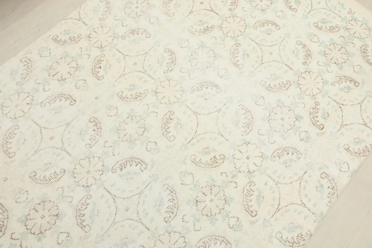 Detailed view of the rug's surface, showcasing the faded green and brown floral and geometric motifs.