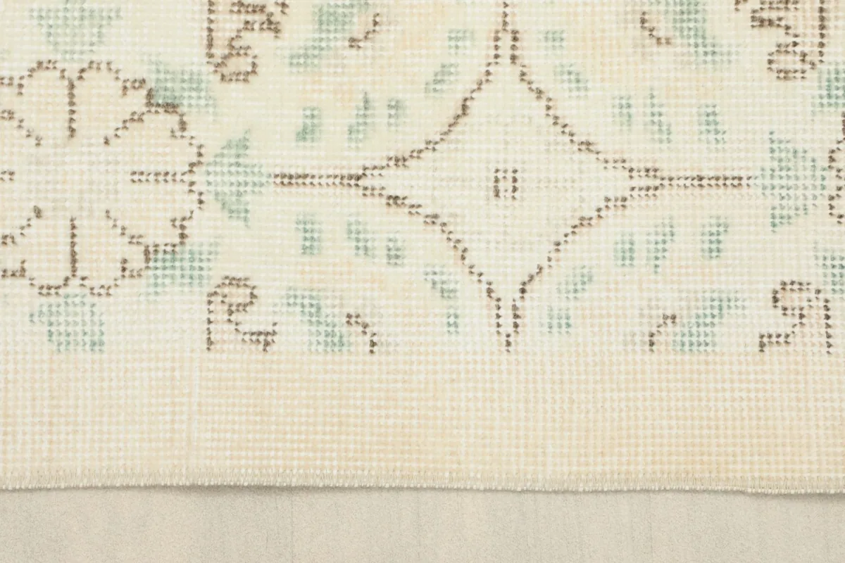 Close-up of the rug's edge and a section of the pattern, showing the low pile and vintage wear.