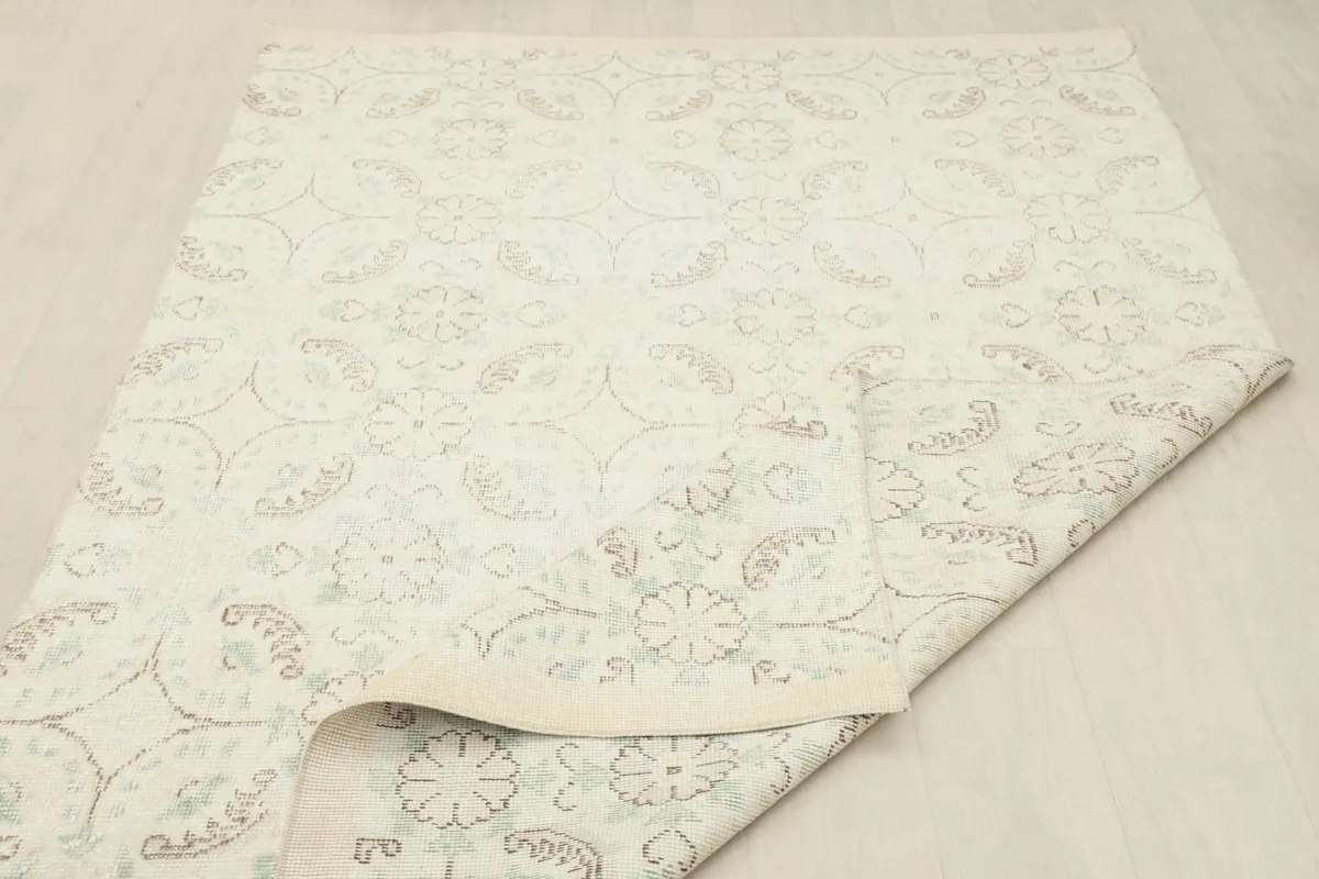 Rug partially rolled, displaying the flexibility of the vintage wool on cotton construction.